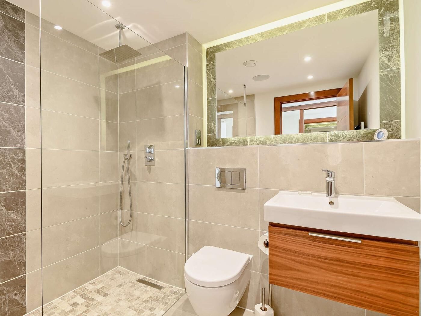 A modern bathroom with a glass-enclosed shower, a toilet, and a vanity with a mirror.