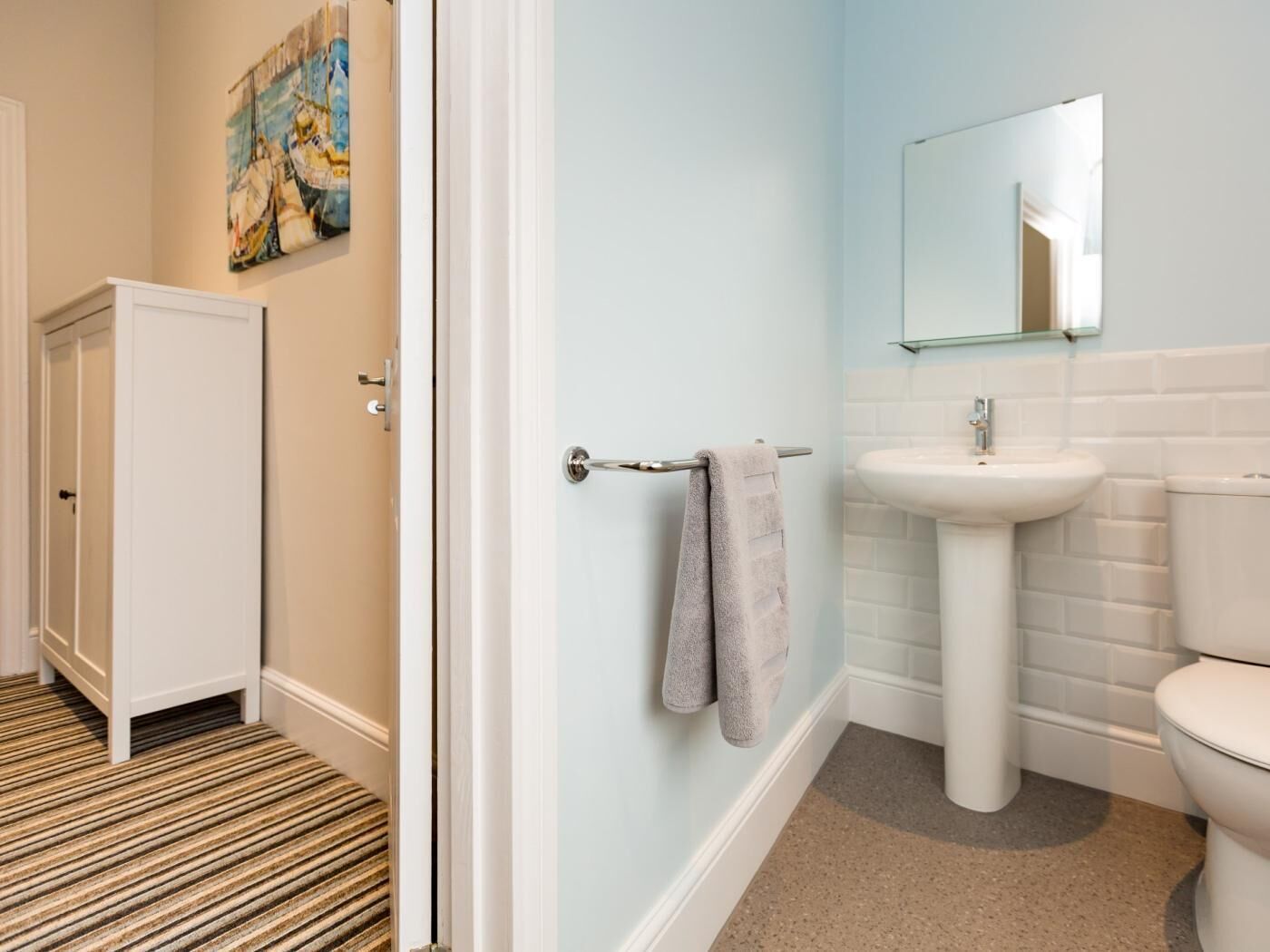 A bathroom with a white sink, a toilet, and a towel rack.