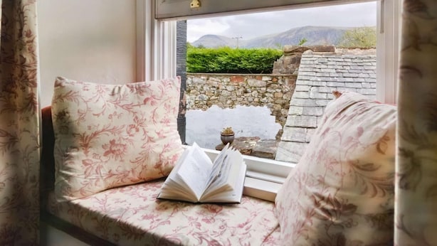 A window seat with a book, a stone wall, and a view of mountains. - 3 Bed in Cleator (oc-sz392) (Ennerdale Bridge)