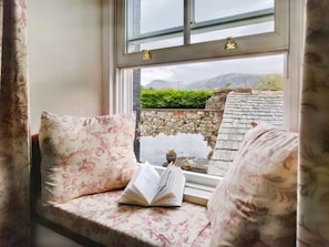 A window seat with a book, a stone wall, and a view of mountains. - 3 Bed in Cleator (oc-sz392) (Ennerdale Bridge)