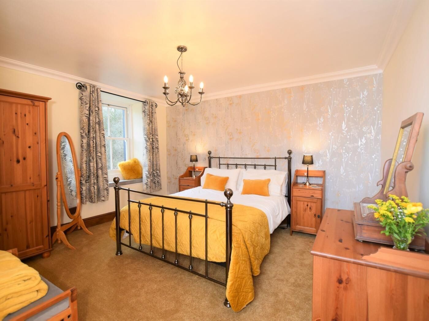 A bedroom with a four-poster bed, wooden furniture, a mirror, and a chandelier.