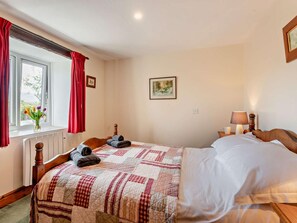 A bedroom with a bed, a window with curtains, a bedside table with a lamp, and a framed picture on the wall. - 2 Bed in Kirkby Stephen (oc-sz265) (Newbiggin-on-Lune)