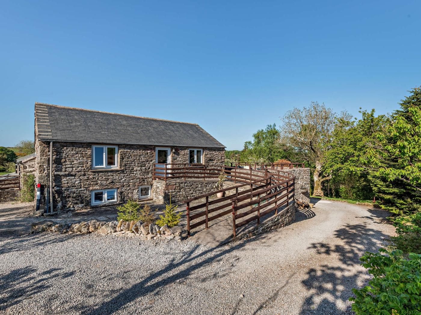 A stone house with a gravel driveway and a wooden fence.