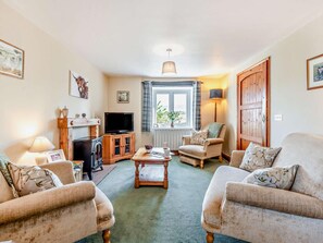 A cozy living room with a television, wooden furniture, a fireplace, and a large window with curtains. - 2 Bed in Kirkby Stephen (oc-sz265) (Newbiggin-on-Lune)