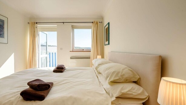 Ein Hotelzimmer mit zwei Betten, einem Fenster mit Vorhängen, einer Lampe und Blick ins Freie.