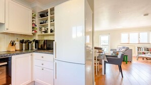 Eine moderne Küche mit weißen Schränken, einem eingebauten Backofen und einem Essbereich mit Tisch und Stühlen.