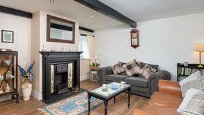 Ein Wohnzimmer mit Kamin, einer Couch, einem Couchtisch und einem Bücherregal.