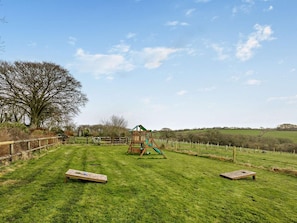 A grassy field with a wooden play structure and two benches. - 2 Bed in Beaworthy (oc-wvttb) (Ashwater)