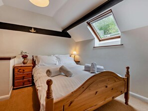 A bedroom with a wooden bed, a nightstand with a vase, a skylight, and a small window. - 2 Bed in Bideford (oc-saill) (Appledore)