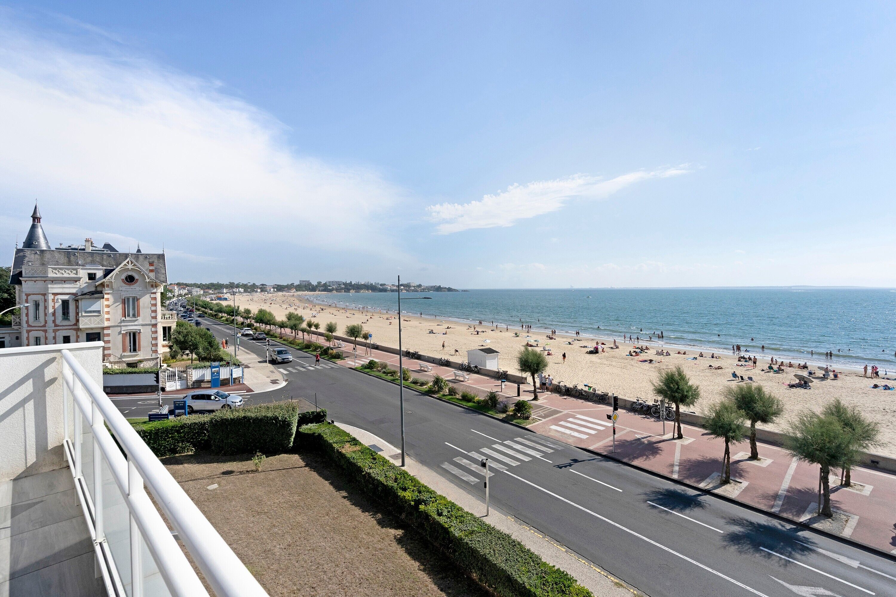 A coastal cityscape with a beach, promenade, and historic buildings.