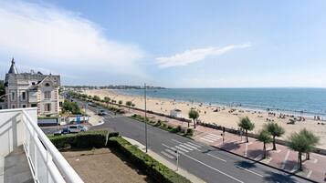 A coastal cityscape with a beach, promenade, and historic buildings.