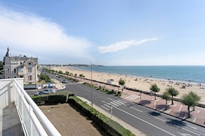 Paisagem costeira com praia, calçadão e edifícios históricos.
