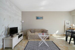 Ein Wohnzimmer mit einer Couch, einem Couchtisch, einem Fernseher und einem Gemälde an der Wand.
