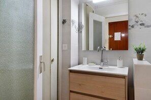 Ein Badezimmer mit Dusche, Waschbecken mit Spiegel und einem Holzschrank.