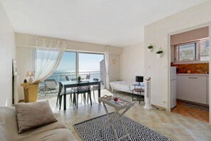 Ein modernes Wohnzimmer mit Sofa, Esstisch und Stühlen, einem Balkon mit Blick sowie einer Küchenzeile.