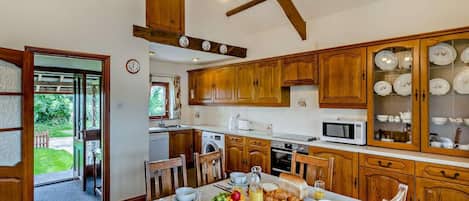 A kitchen with wooden cabinets, a dining table set with breakfast, and a view of the outdoors.