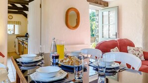 Zona pranzo con tavolo apparecchiato per quattro, un divano rosso e vista sul giardino attraverso una finestra.