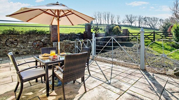 Eine Terrasse mit Tisch, Stühlen und Sonnenschirm.