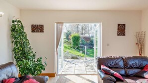 Ein Wohnzimmer mit einer Couch, einem Couchtisch, einer Topfpflanze und einer Schiebetür zu einer Außenpatio.