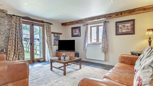 A living room with a sofa, a coffee table, a TV, and a fireplace. - 3 Bed in Winkleigh (oc-1450b) (Iddesleigh)