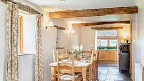 A rustic dining area with wooden furniture, a stone floor, and exposed wooden beams. - 3 Bed in Winkleigh (oc-1450b) (Iddesleigh)