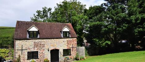 A stone house with a tiled roof, a front door, and two windows.