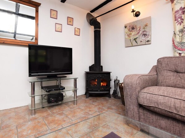 A living room with a television on a glass stand, a fireplace, and a sofa.