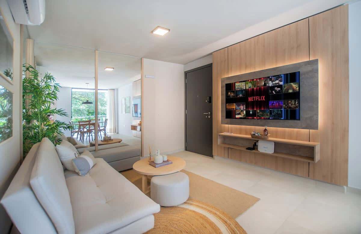 A modern living room with a sofa, a coffee table, a TV wall unit, and a dining area with a table and chairs.
