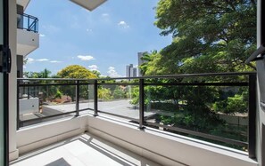 A balcony with a glass railing, a view of a residential area, and a clear sky. - Corporate Stays Insignia City - B32 (Asunción)