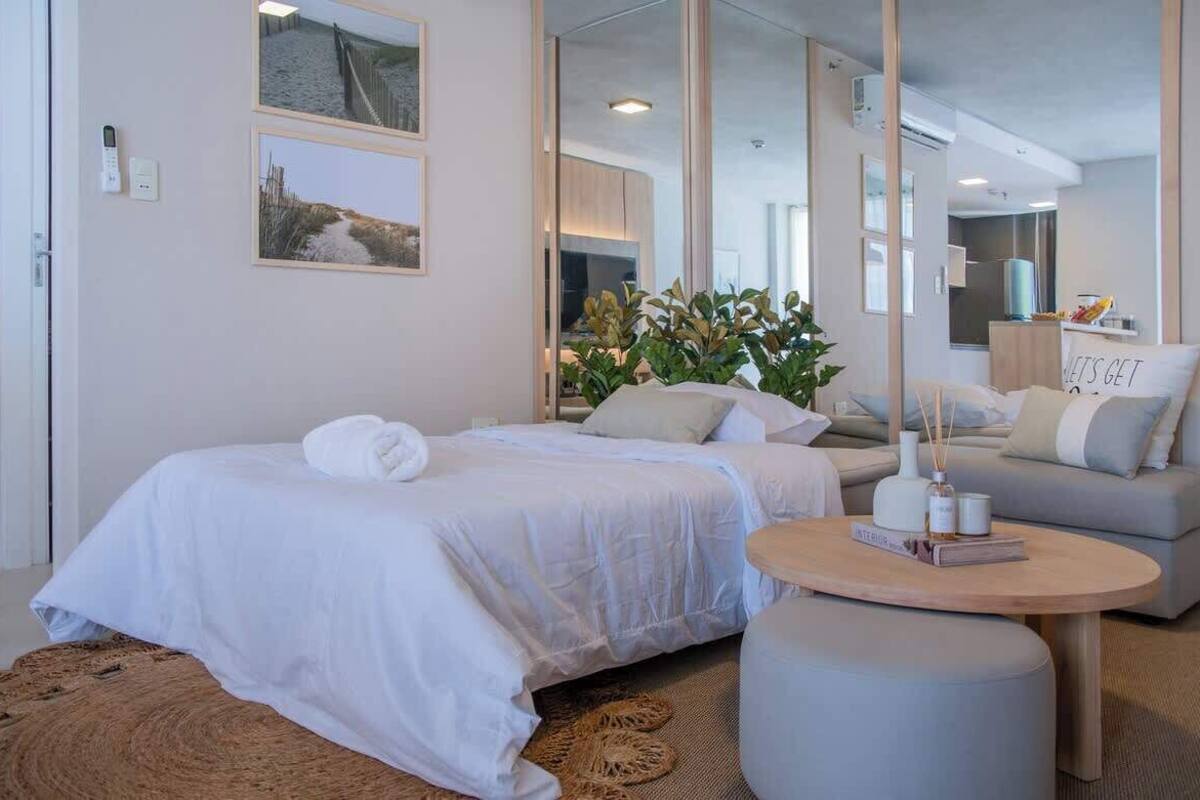 Una habitación de hotel moderna con cama, sofá, mesa redonda y espejo.