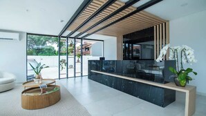 Ein modernes Interieur mit einem schwarzen Marmor-Rezeptionstresen, Holzdielen an der Decke und einer großen Glasdoor zum Außenbereich.