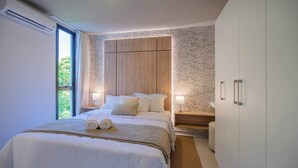 Ein Schlafzimmer mit einem großen Bett, Nachttischen, einem Kleiderschrank und einem Fenster.
