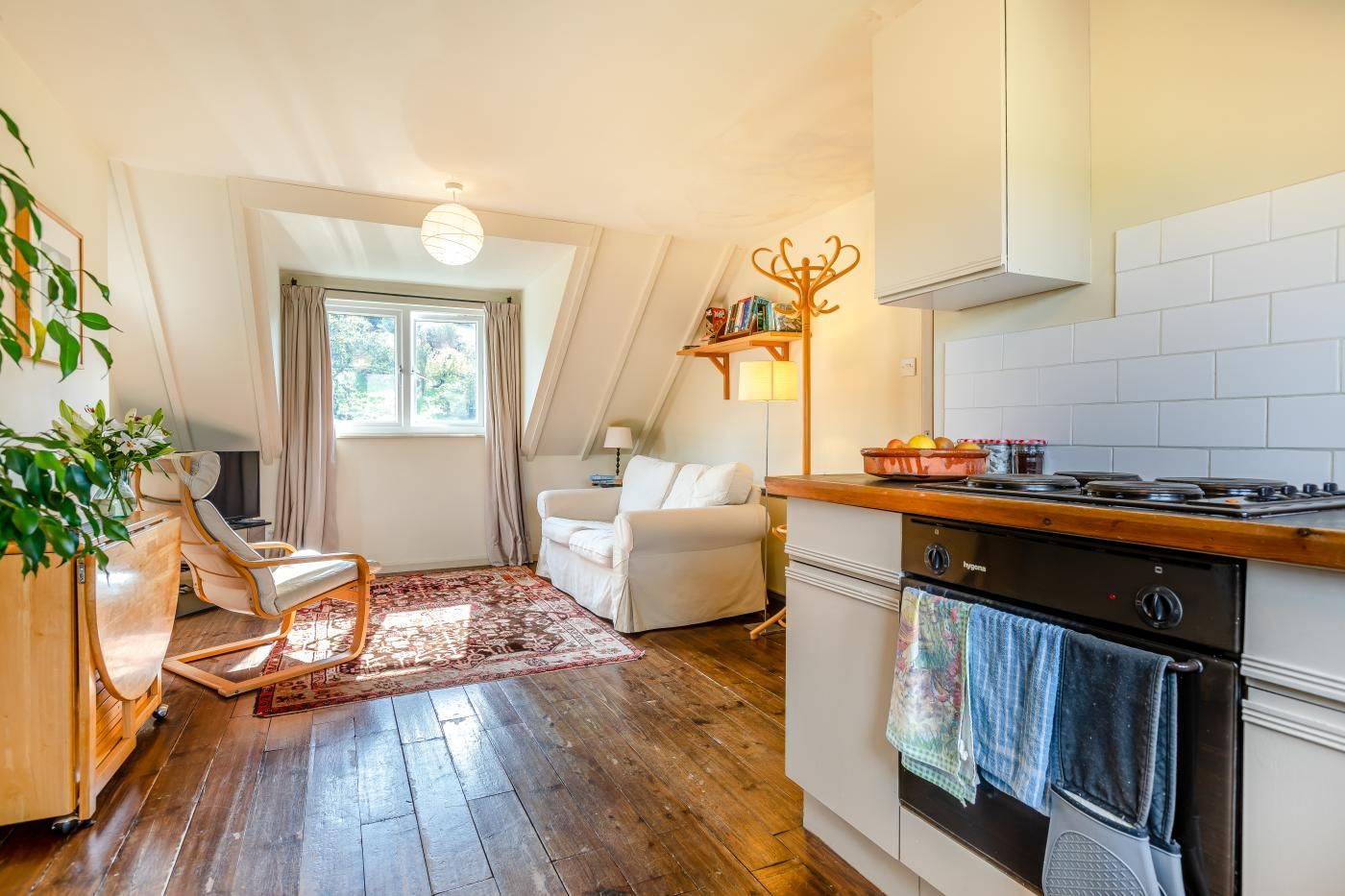 A cozy kitchen with a stove, oven, and a dining area with a chair and table.