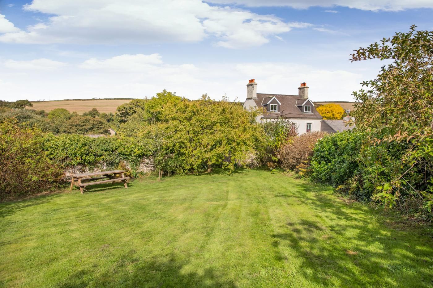 A house with a well-maintained lawn and a wooden bench.