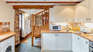 A kitchen with white cabinets, a microwave, a toaster, and a washing machine. - 3 Bed in Bideford (oc-burfl) (Higher Clovelly)