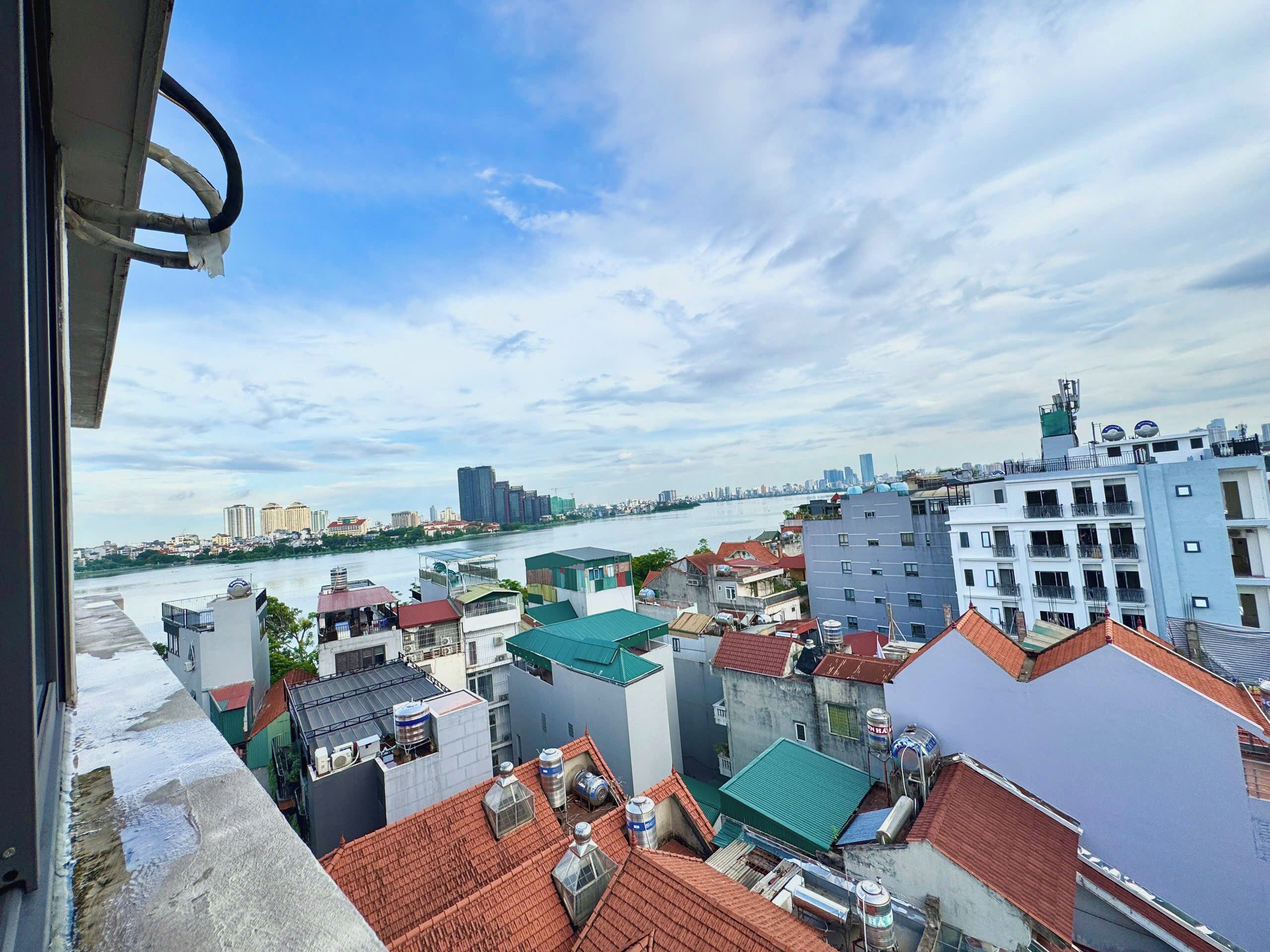 A cityscape with a river, buildings with red and grey roofs, and a clear sky.
