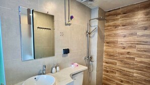 Et moderne badeværelse med to håndvaske, toilet, bruser og en trævæg.