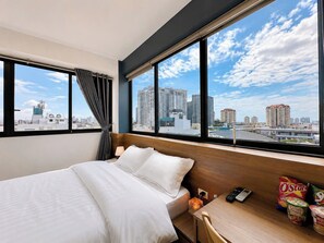 A hotel room with a bed, a desk, and a view of the cityscape. - Soleil Homestay (Hanoi)
