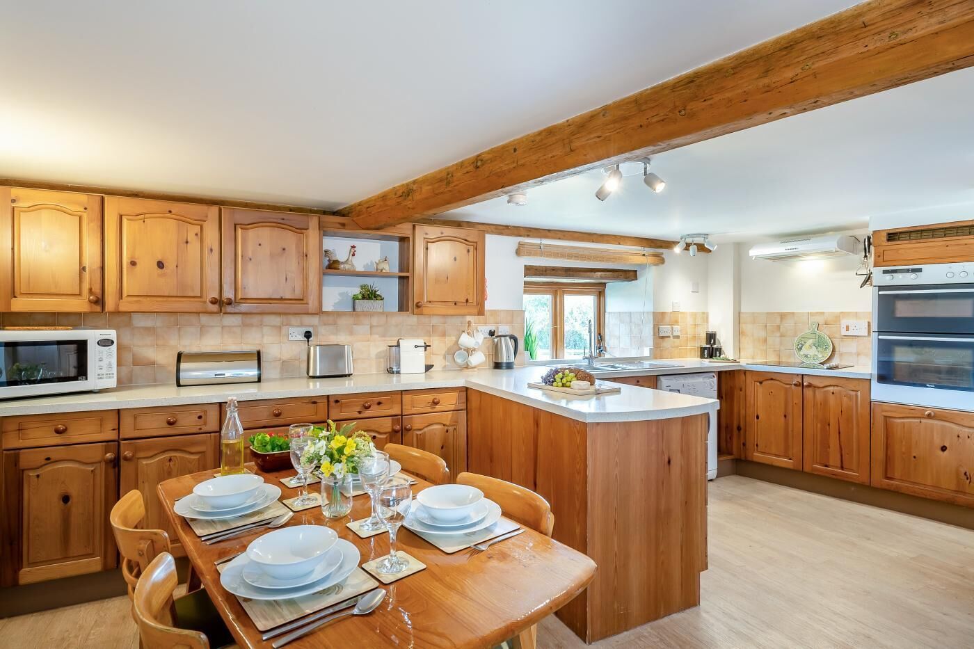 Una cocina con gabinetes de madera, una isla central y una mesa de comedor preparada para cuatro.