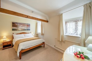 A bedroom with a wooden bed, bedside lamps, a window with curtains, and a painting on the wall. - 2 Bed in Wellington (oc-cider) (Blackmoor)