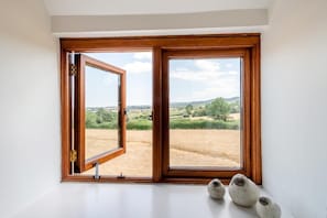 A room with a large wooden-framed window, a white wall, and a small table with two ceramic objects. - 2 Bed in Wellington (oc-cider) (Blackmoor)