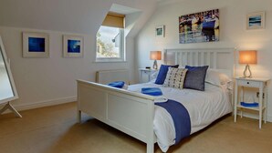 Een slaapkamer met een bed, nachtkastjes, een raam en kunstwerken aan de muur.