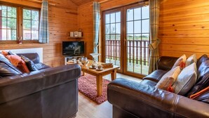 Ein Holzblock-Innenraum mit Ledersofa, Fernseher und Tisch mit Tassen.