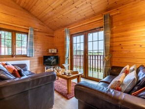 Ein Holzblock-Innenraum mit Ledersofa, Fernseher und Tisch mit Tassen.