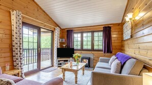 Ein gemütliches Blockhaus-Interieur mit Kamin, Fernseher und einer bequemen Sitzecke.