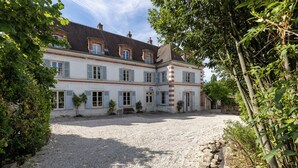 Ein großes, historisches Gebäude mit vielen Fenstern und einem Kieshof.