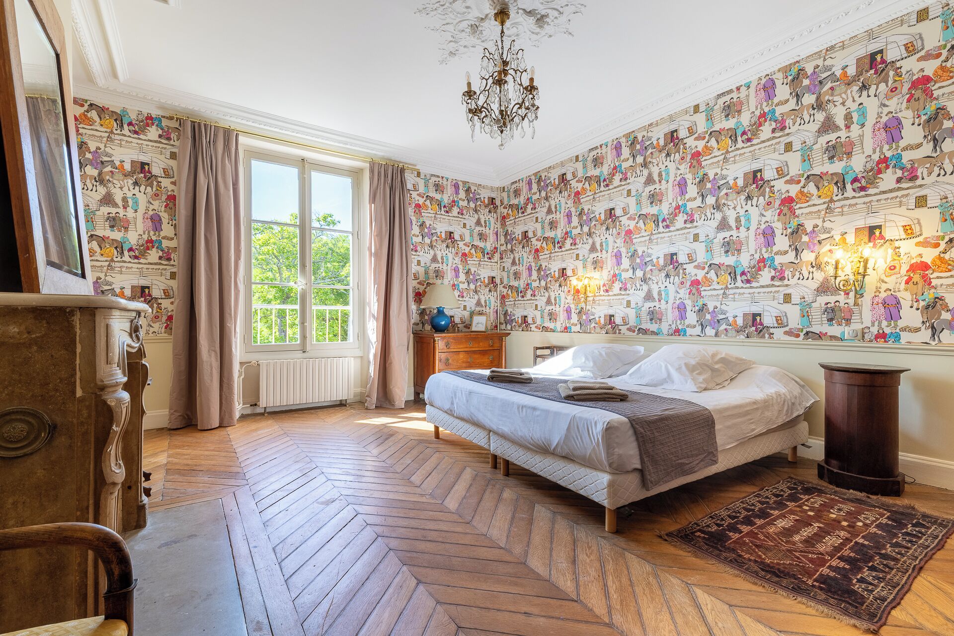 Une chambre avec un grand lit, un lustre, un plancher en bois et une fresque murale.