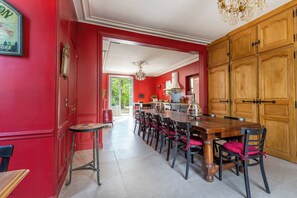 Comedor con una larga mesa de madera, paredes rojas y una araña.