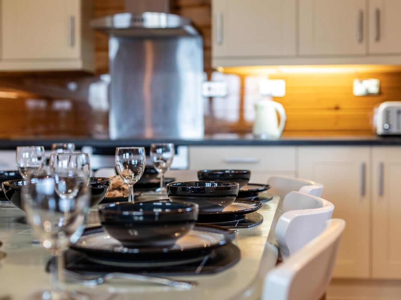 A modern kitchen with a dining table set for four, a coffee maker, and a toaster.