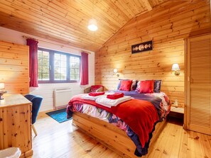 Een slaapkamer met houten lambrisering, een bed, een bureau en een raam.
